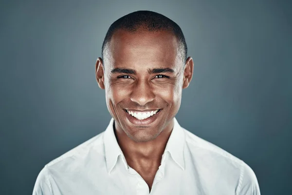 Beau et heureux. Charmant jeune homme africain en chemise regardant la caméra et souriant tout en se tenant debout sur fond gris — Photo