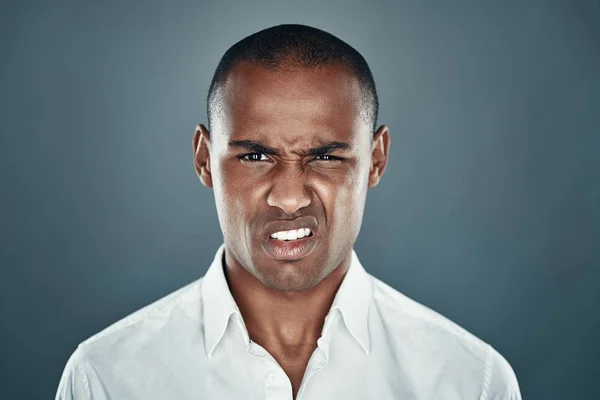 Disgust. Young African man in shirt looking at camera and frowning while standing against grey background