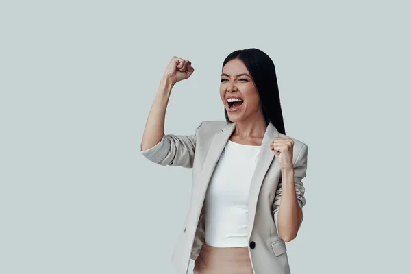 ¡Gané! Atractiva joven mujer asiática haciendo gestos y sonriendo mientras está de pie sobre fondo gris —  Fotos de Stock