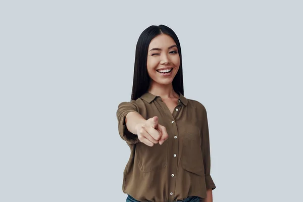 ¡Te necesito! Hermosa mujer asiática joven mirando a la cámara y sonriendo mientras está de pie sobre fondo gris —  Fotos de Stock