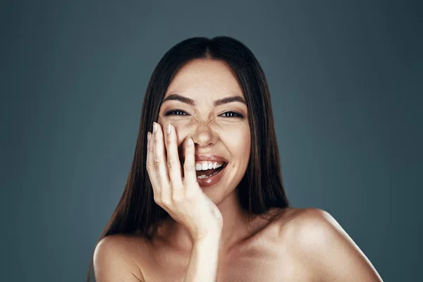 Belleza natural. Hermosa mujer asiática joven mirando a la cámara y sonriendo mientras está de pie sobre fondo gris —  Fotos de Stock