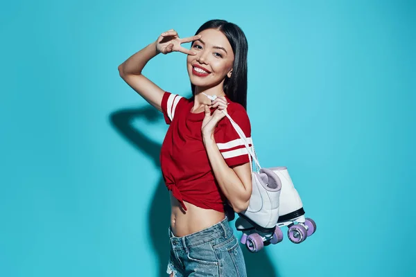 Sentindo-se livre e feliz. Jovem mulher asiática atraente sorrindo e olhando para a câmera enquanto está de pé contra o fundo azul — Fotografia de Stock