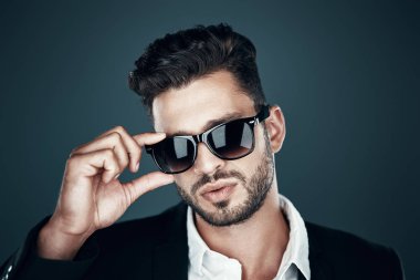 Gri arka plan karşısında dururken gözlük ayarlama ve kamera bakarak formalwear Charming genç adam