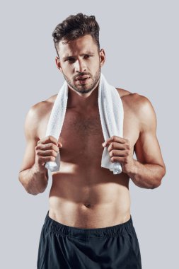 Gri arka planda dururken kameraya bakan spor giyim yakışıklı genç adam