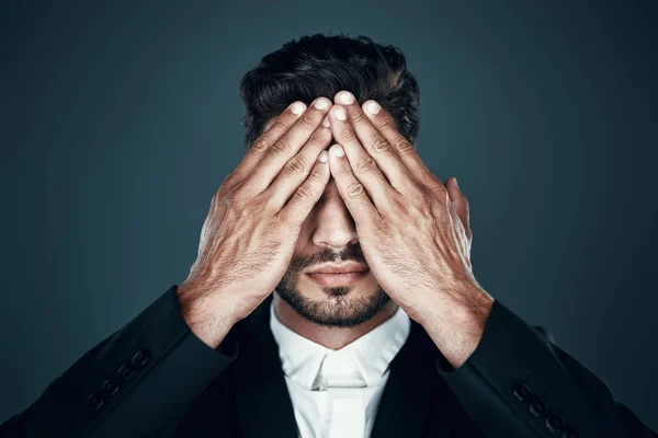 Okouzlující mladý muž ve formální oblečení zakrývající oči rukama, zatímco stojí proti šedému pozadí — Stock fotografie