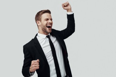 Gri arka plan aleyhine dururken formalwear tezahürat ve gesturing yakışıklı genç adam