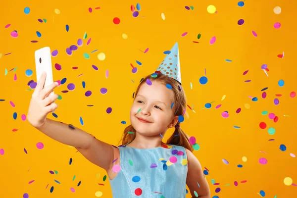 Cheerful little girl celebrates birthday. The child holds the ph — Stock Photo, Image