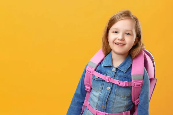 Portret van een klein meisje schoolmeisje met een rugzak op een gele achtergrond. Het kind close-up. Terug naar school. Het begrip onderwijs. — Stockfoto