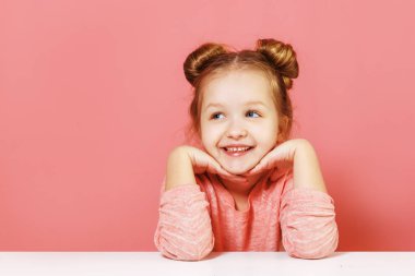 Pembe arka plan üzerinde kenara bakarak çörekler ile güzel güzel çekici büyüleyici winsome neşeli küçük çocuk kız yakın çekim portre