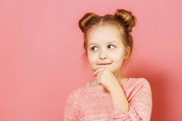 Pembe arka plan üzerinde bir kenara düşünceli görünümlü çörekler ile güzel güzel çekici büyüleyici winsome küçük çocuk kız yakın çekim portre