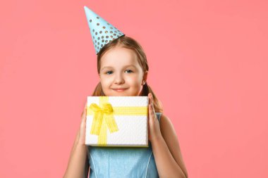 Şapkalı mutlu küçük kızın elinde hediye olan bir kutu var. Pembe mercan arka plan üzerinde bir bebek portresi. Kopyalama alanı.