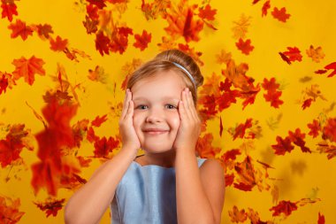 Düşen sonbahar yapraklarının arka planında küçük bir kız. Sonbahar, tatil, cadılar bayramı, satış kavramı.