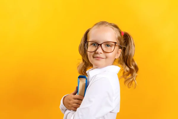 Veselá studentka v brýlích, držící knihy na žlutém pozadí. Pojetí vzdělání a školy. — Stock fotografie