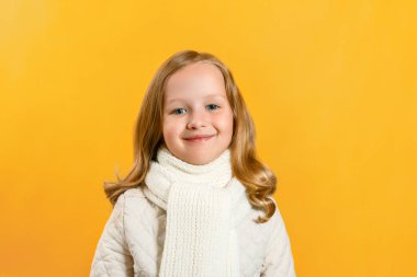 Sarı bir arka plan üzerinde bir ceket ve eşarp sevimli sevimli küçük kız Portresi. Sonbahar konsepti. Kopyalama alanı