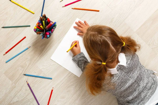 Top view of a little girl lying and painting on the floor in her room at home. — Stock Photo, Image