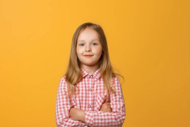 Sarı arka plan üzerinde komik bir küçük sarışın kız Closeup portre. Pembe gömlekli bir çocuk kameraya bakıyor..