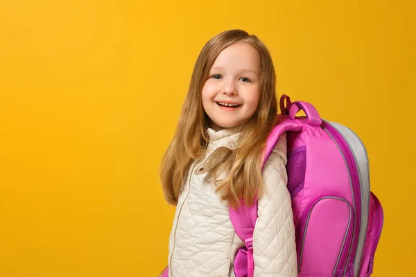 Ritratto di una scolaretta in giacca con zaino su sfondo giallo. Torniamo a scuola. Il concetto di istruzione. Copia spazio — Foto Stock