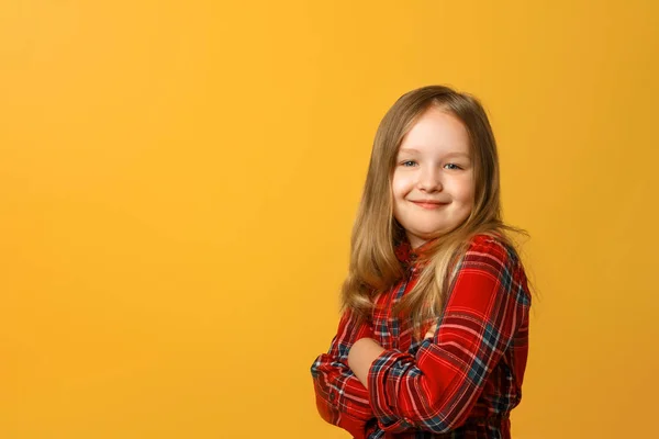 Portrét zábavné malé blonďaté dívky v červených šatech na žlutém pozadí. — Stock fotografie