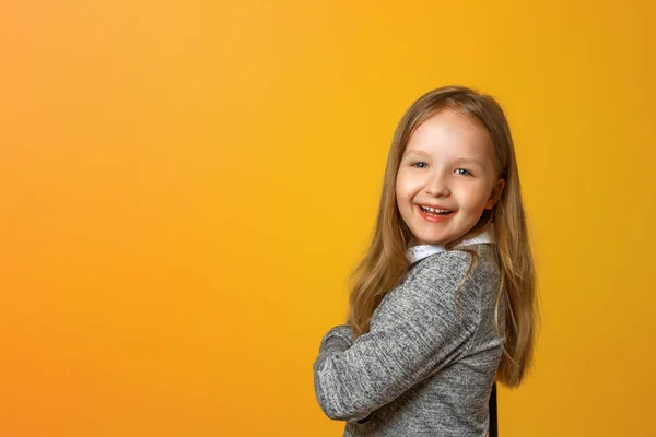 Portrét zábavné malé blonďaté dívky na žlutém pozadí. — Stock fotografie