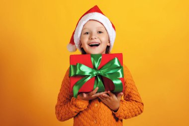 Noel hediyesi olan mutlu küçük kız. Noel baba şapkalı bir çocuk hediye içeren bir kutu tutar.