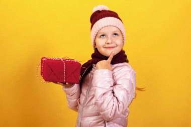 Sarı bir arka plan üzerinde bir ceket, eşarp ve şapka sevimli bir küçük kız portresi. Çocuk bir hediye ve hayalleri ile bir kutu tutar