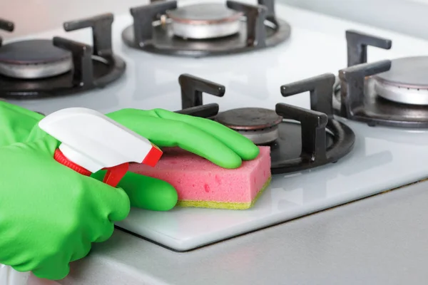 Close-up van de hand in beschermende handschoen met flesspray en spons. Keuken schoonmaken, gasfornuis — Stockfoto