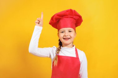 Sarı arka planda şef gibi giyinmiş güzel bir kız. Bir çocuk boş alanda işaret parmağını yukarı doğru gösterir