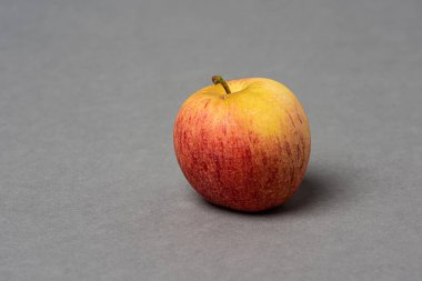 Gri arkaplanda kırmızı ve sarı elma.