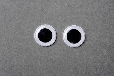 Gri arka plandaki şaşı gözler ileriye bakıyor..