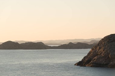 Gün batımında deniz kenarındaki sarp kayalıkların manzarası.