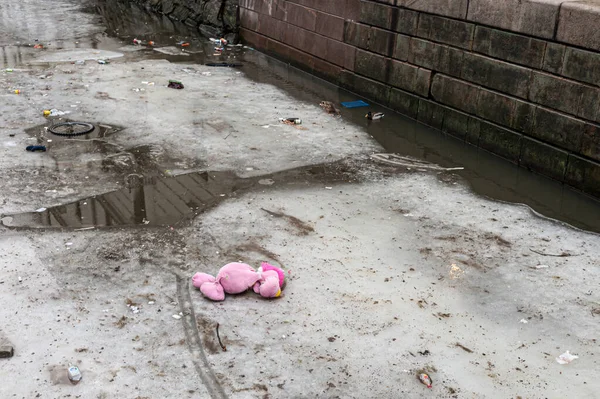 Trash, a bike wheel and a big pink soft toy on the partly melted ice in a canal.