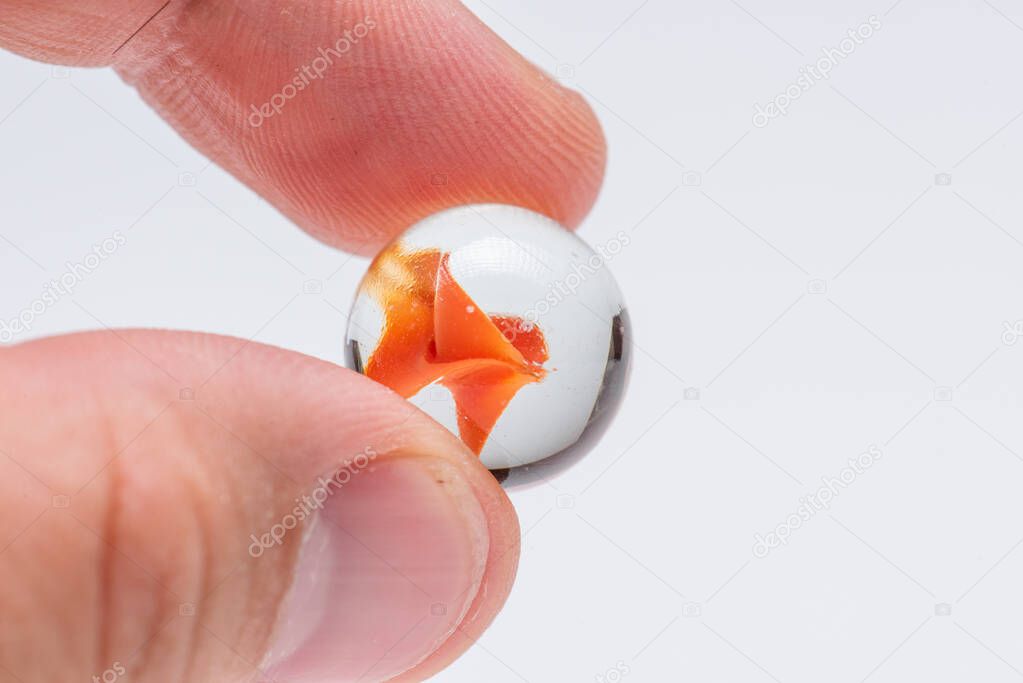 Orange glass marble held by two fingers