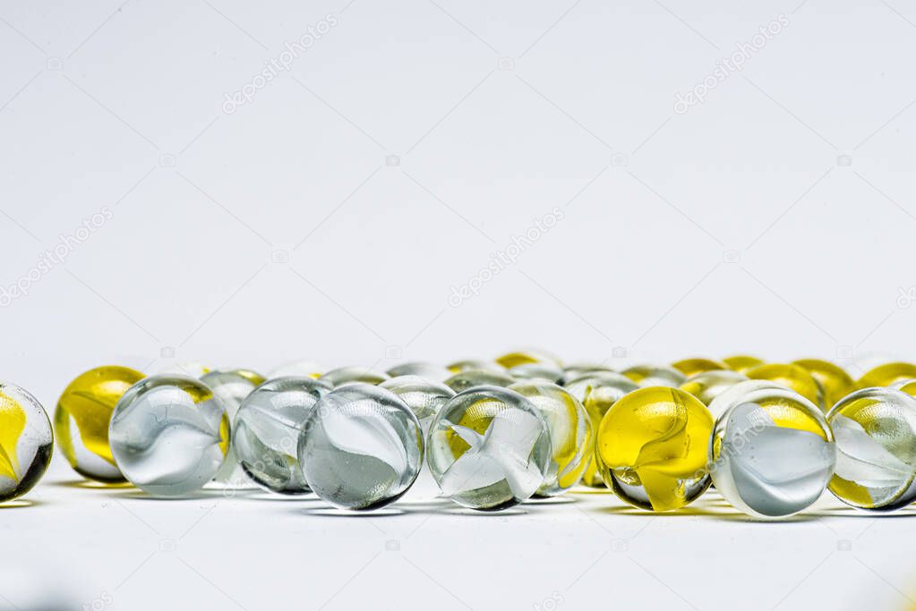 Yellow and white glass marbles on a table.