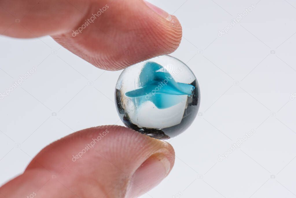 Blue glass marble held by two fingers