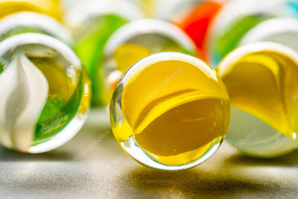 Yellow, green, blue and red glass marbles on a table.