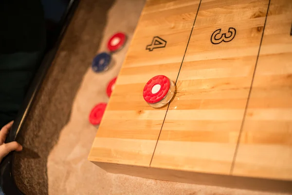 Kırmızı disk, bir shuffleboard masasında ancak 4 puanlık bir alanda.