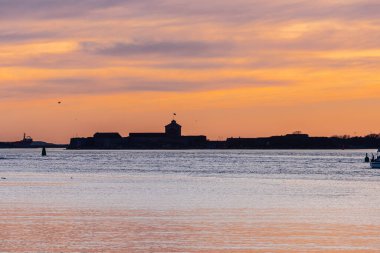 Gün batımında eski bir sahil kalesinin solueti..