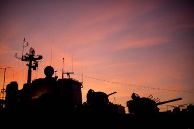 Emekli bir savaş gemisinin silueti kızıl bir günbatımına karşı