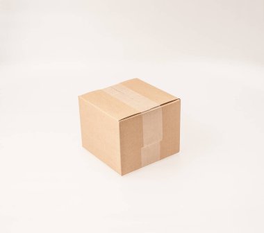 Beyaz arka planda kahverengi, küçük, karton bir kutu.