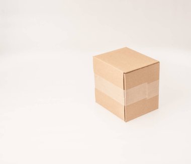 Beyaz arka planda kahverengi, küçük, karton bir kutu.