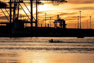 Su motosikleti gün batımında körfezde hızla ilerliyor.