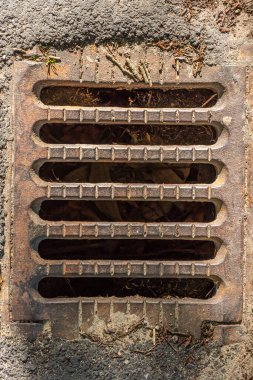 Yolun kenarında küçük bir kanalizasyon ızgarası.