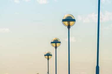 Güneş ışığında arka arkaya lamba direkleri.