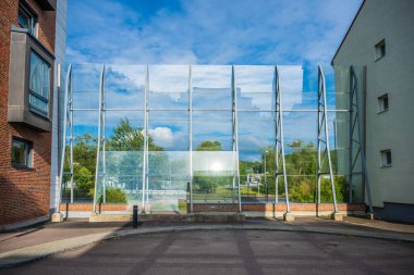 Gökyüzünü ve ağaçları yansıtan modern cam duvar