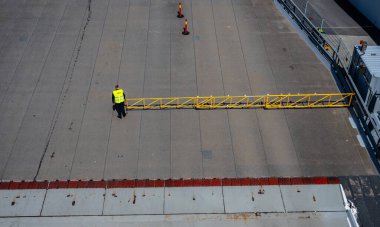 İşçiler beton yüzeyde güvenlik bariyerini hareket ettiriyor