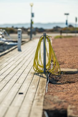 Marinadaki ahşap rıhtımda sarılı sarı hortum.