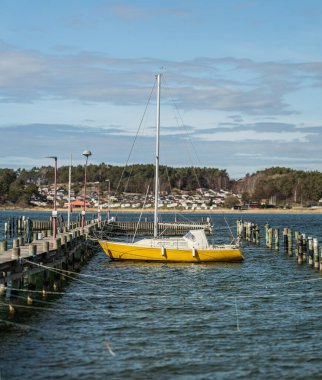 Açık sarı yelkenli boş bir limana demirlemiş.