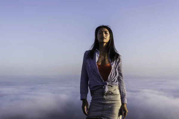 Gün batımında bulutların üzerinde bir dağın tepesinde bir kadın portresi