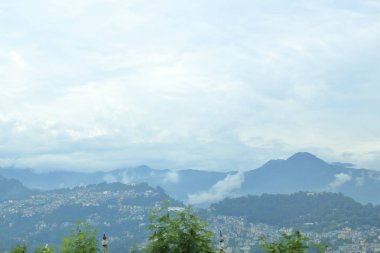 Dağların ardında bulutlarla kaplı dağlar ve şehir görülebilir, Sikkim, Hindistan.