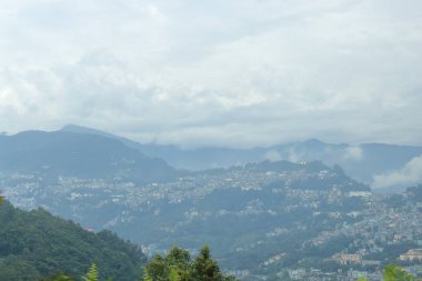 Dağların ardında bulutlarla kaplı dağlar ve şehir görülebilir, Sikkim, Hindistan.